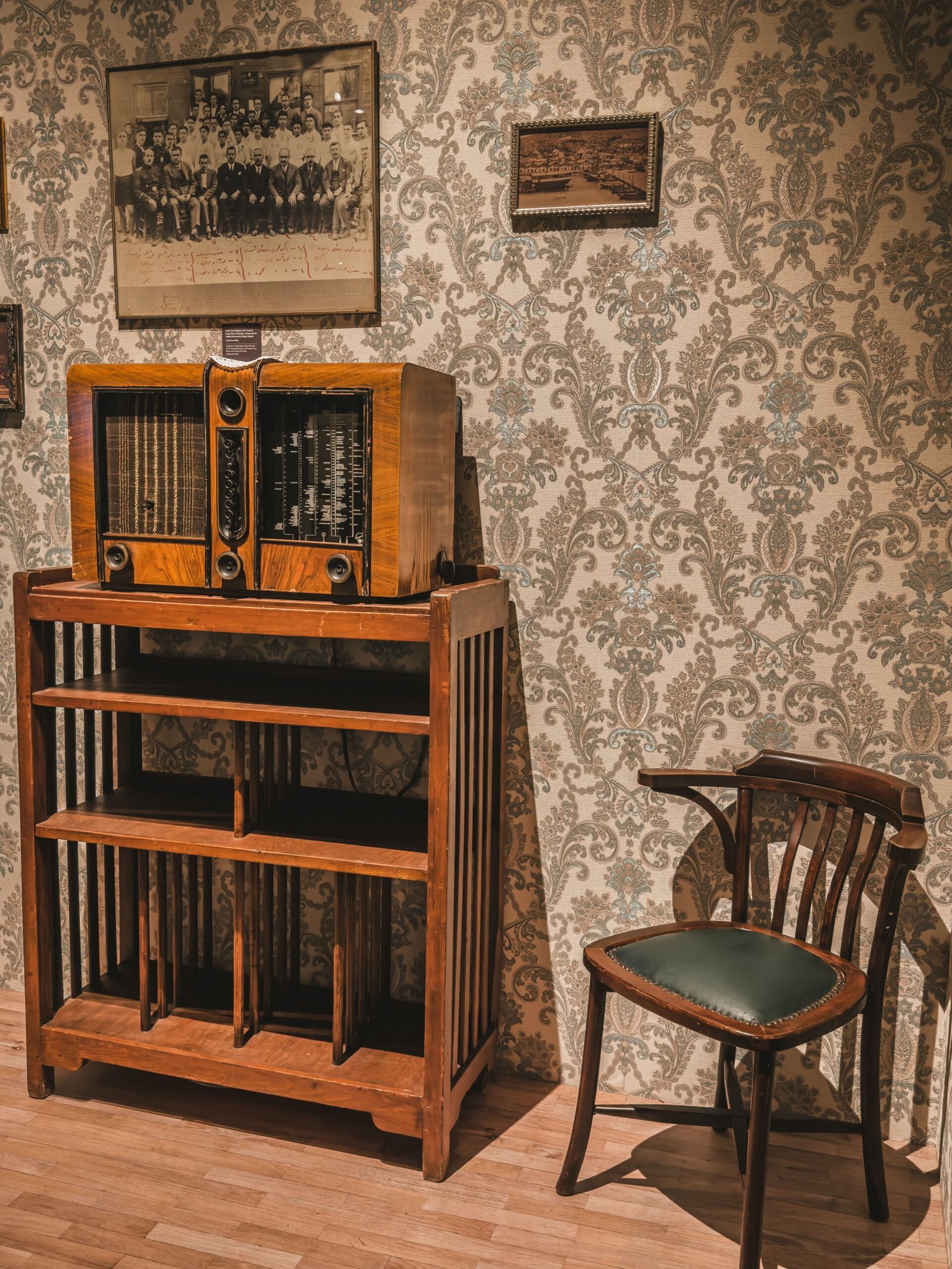 A vintage room featuring an antique radio on a wooden cabinet with a retro chair.